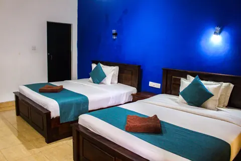 Two beds with teal runners against a deep blue wall